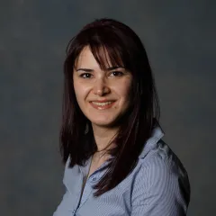 A professional headshot of Shaghayegh Navabpour wearing a button up shirt against a grey background.