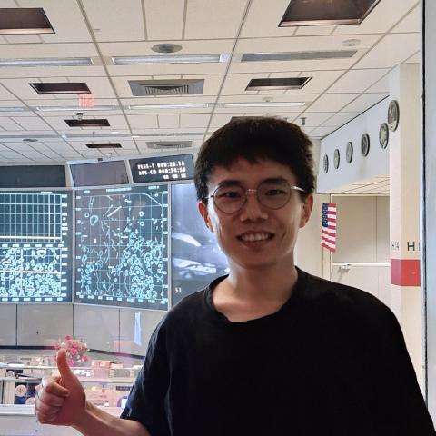 A headshot of Sangsin Lee, smiling and wearing a blue T-shirt. The background is simple and light gray, emphasizing a casual yet professional vibe.
