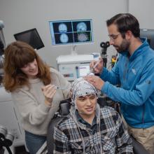 Corey Keller and Milena Kaestner work to prepare a research subject for simultaneous EEG recording and TMS brain stimulation in the Koret Human Neurosciences Community Laboratory at the Wu Tsai Neurosciences Institute.